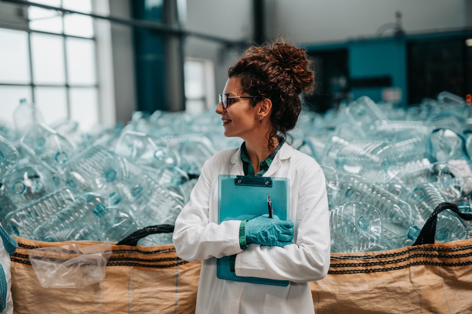 Young happy female worker in bottling factory recycling department. Inspection quality control.