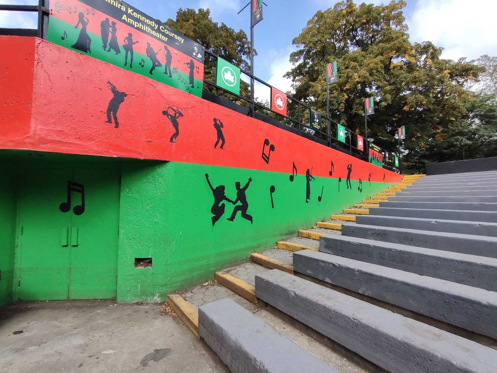 Artwork of musicians and notes on a red and green wall at an amphitheater. 