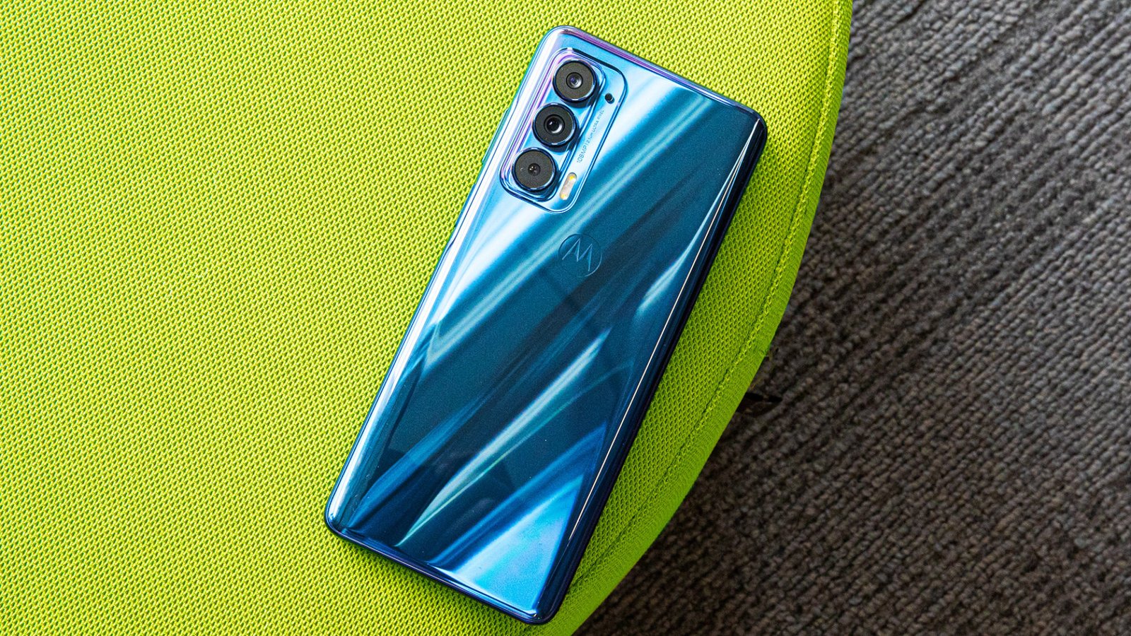 A Motorola Edge 5G smartphone face down on a green cushion on a table.  